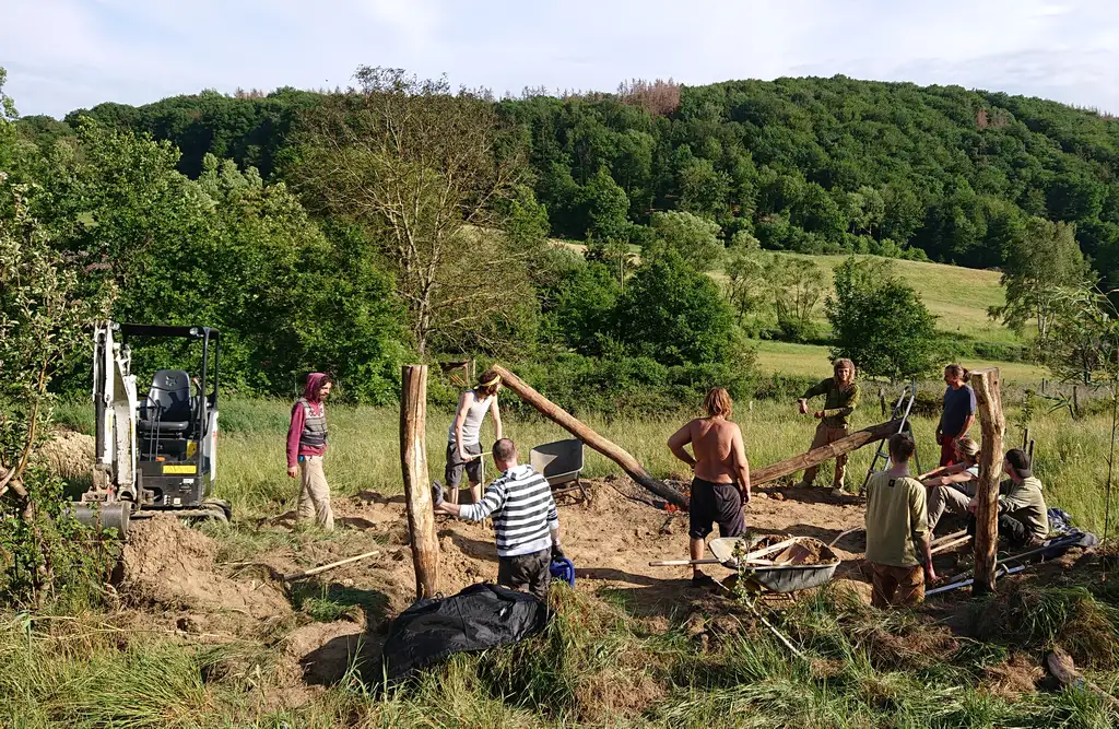 Kursgruppe beim Bau auf der zwei Hektar großen Fläche, dahinter Wald und Hangwiese